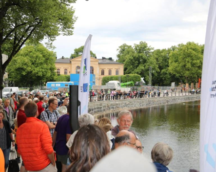 En folkmassa står längs ett vattendrag.