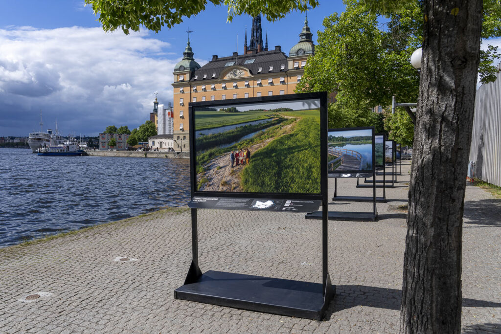 Stora bilder uppställda utomhus vid vatten, i stadsmiljö