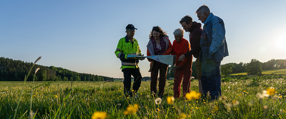 Flera personer står utomhus och tittar på en karta.