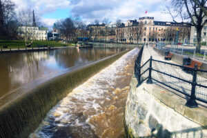 Forsande ström i faunapassagen, till höger i bilden, med stadsmiljö i bakgrunden